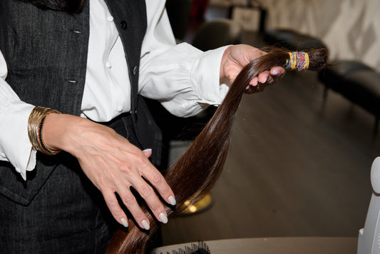 Hands smoothing the lengths of a long human hair wig